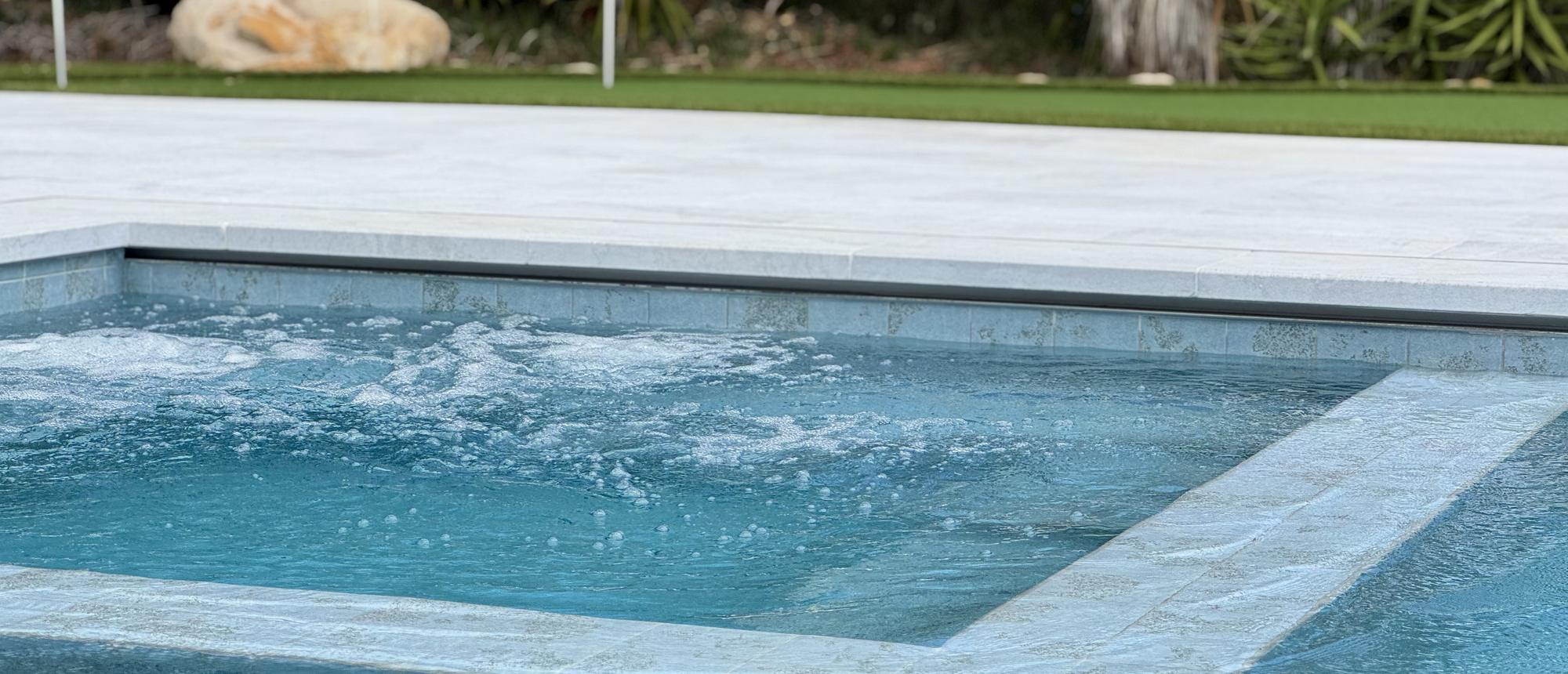 Pool edge with a raised spa, boulders and agave planting