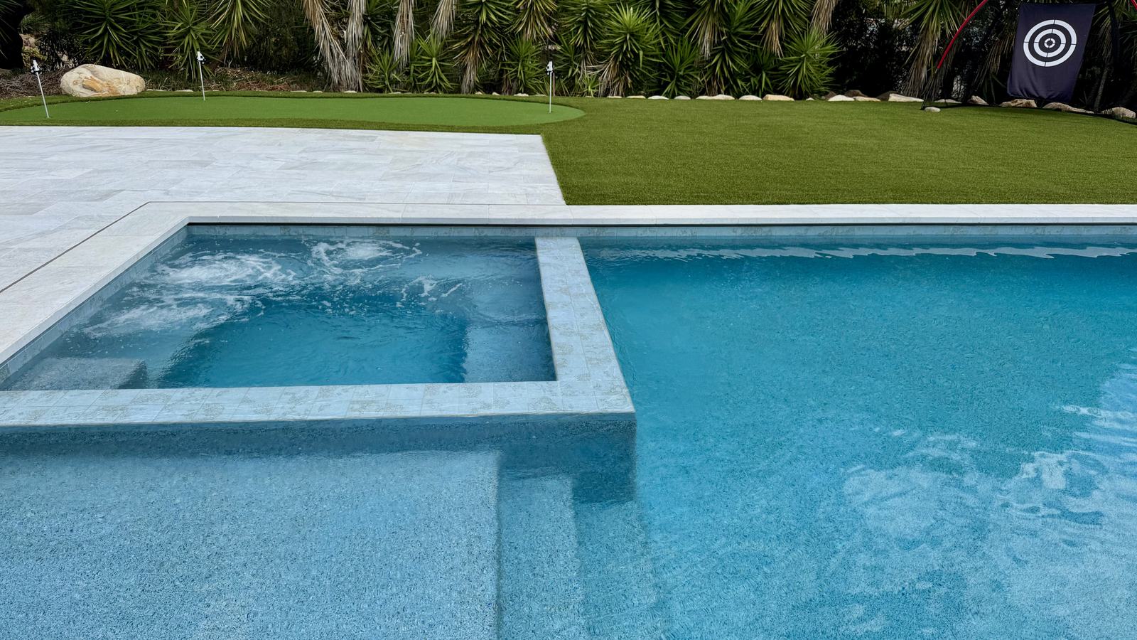 The same backyard finished, with the spa, pool and putting green in