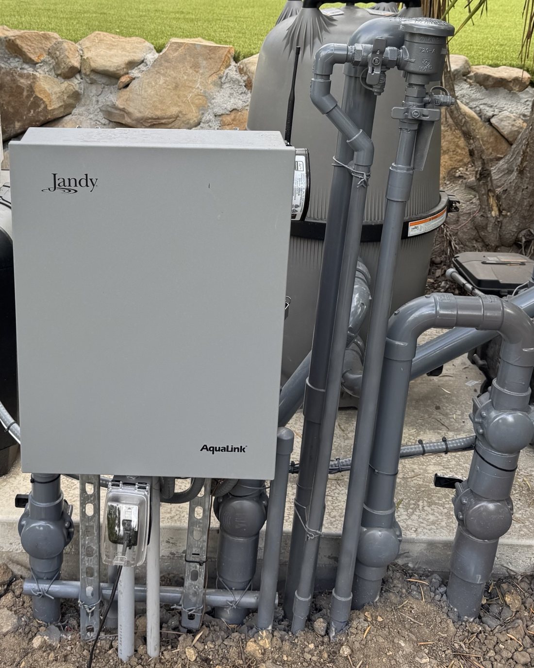Jandy equipment pad: AquaLink automation panel, cartridge filter and pump beside the lawn