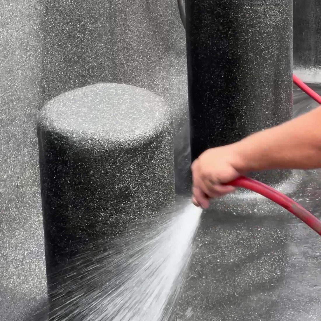 Hose washing down a fresh pebble finish on a swim-up stool