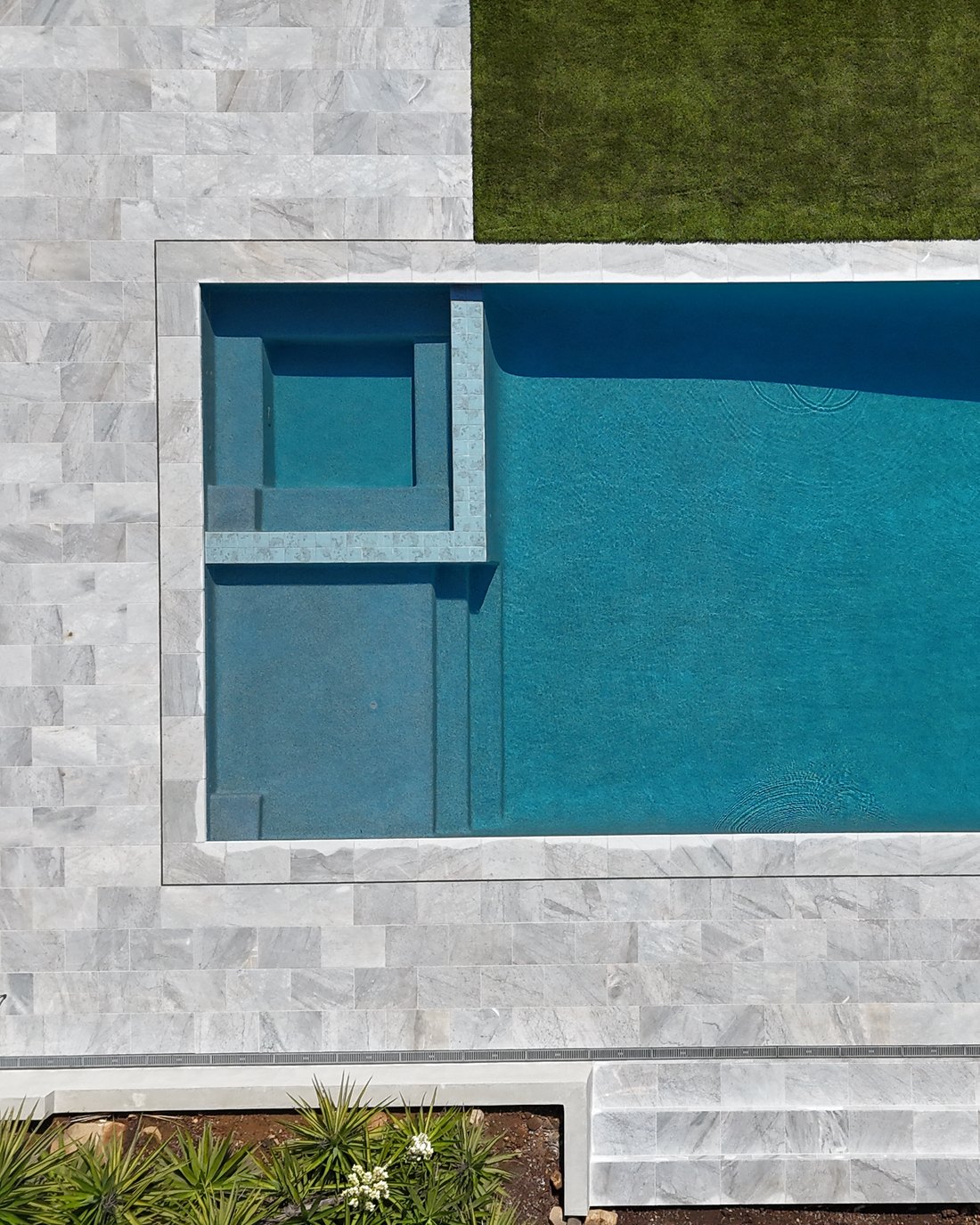 Raised spa set into the corner of a geometric pool, seen from above