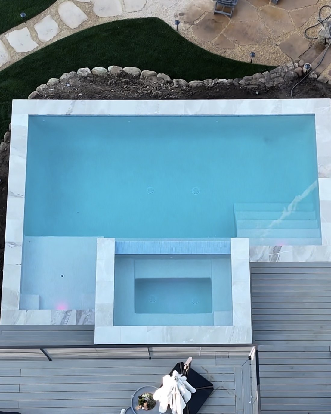 Pool with a spillover spa, light finish and composite deck, seen from above