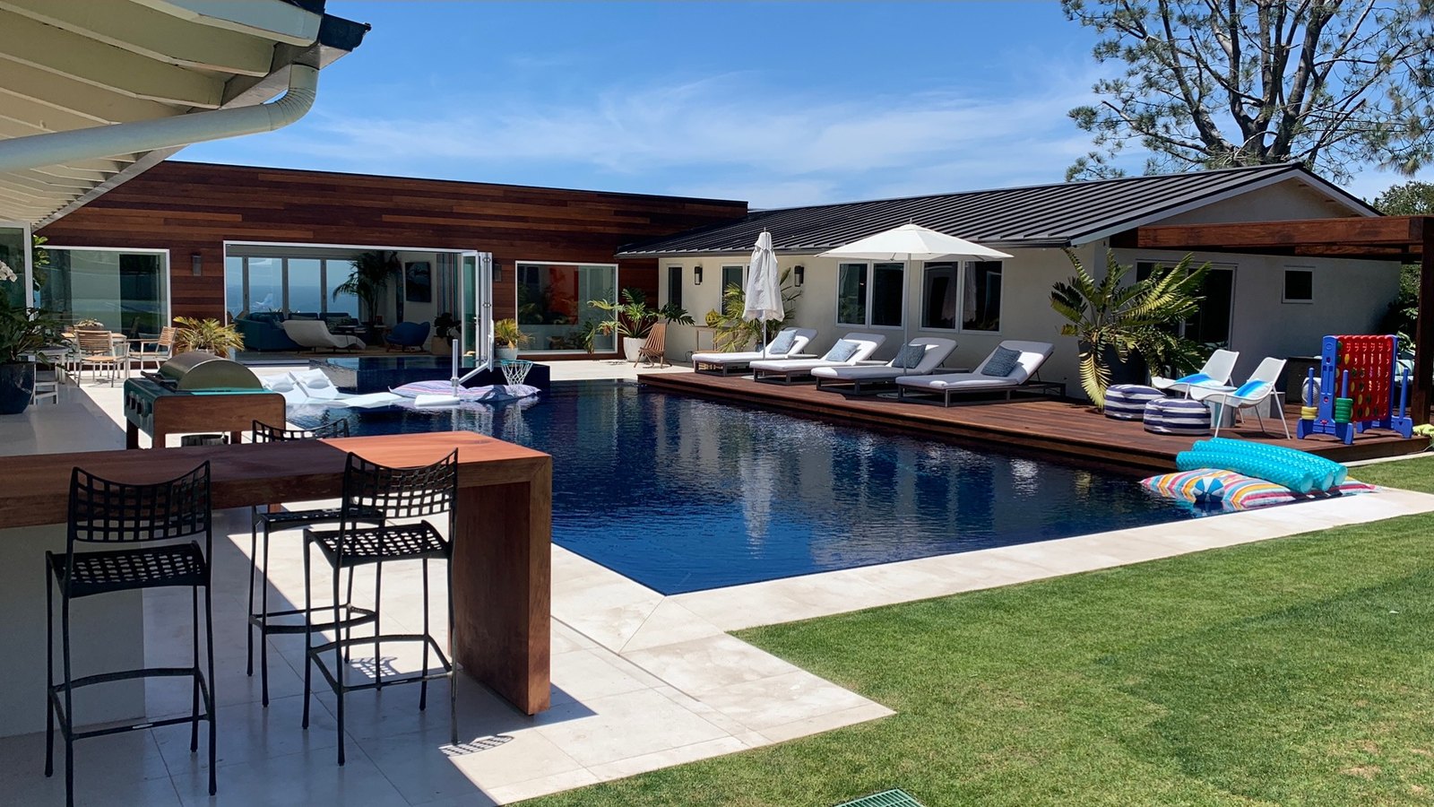 Finished pool with wood deck, loungers and an outdoor kitchen