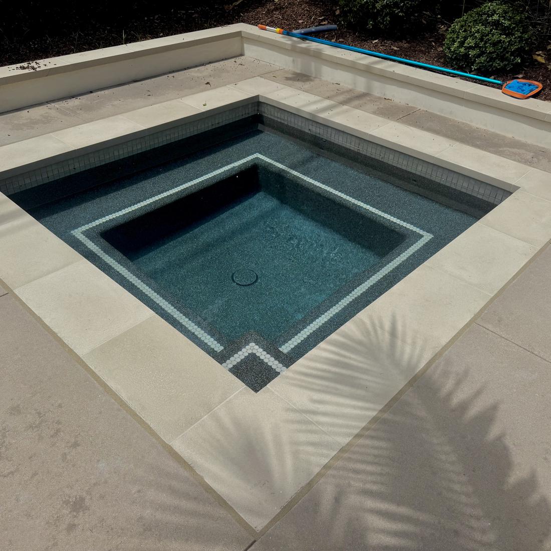 Geometric spa with a dark interior finish and crisp stone coping