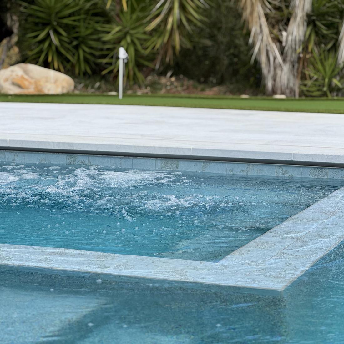 Pool edge with a raised spa, boulders and agave planting