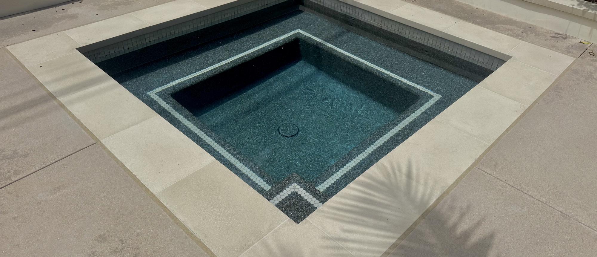 Geometric spa with a dark interior finish and crisp stone coping